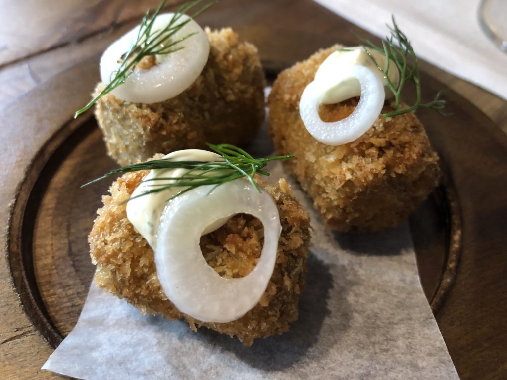 croquetas de asado ahumado con emulsión de Merken Mapuche, bocado cárnico, de rebozado grueso, que recuerdan a las croquetas de rabo de toro o de puchero.