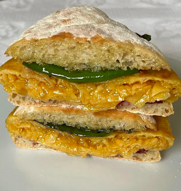 Mollete relleno de tortilla de patatas con pimientos verdes fritos y salchichón ibérico.